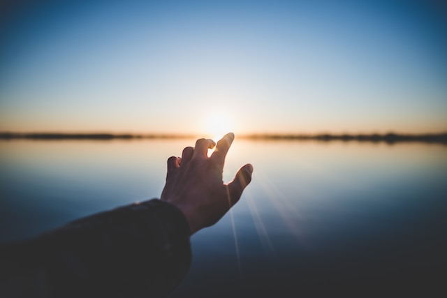 photo of hand touching sunset horizon